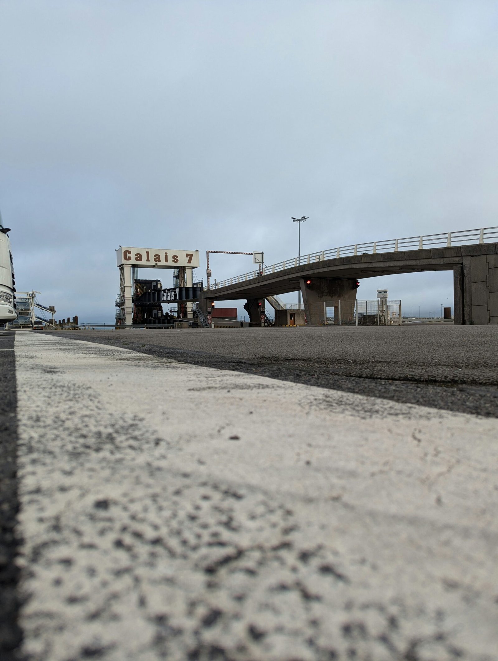 A white truck driving down a road next to a bridge